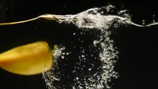 Pimentos doces amarelos, capsicum annuum, Vegetais caindo na água contra fundo preto — Vídeo de Stock