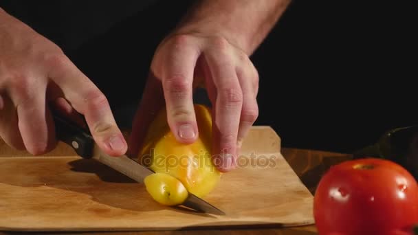 Une main de cuisinier coupe un poivron au couteau sur une planche à découper — Video