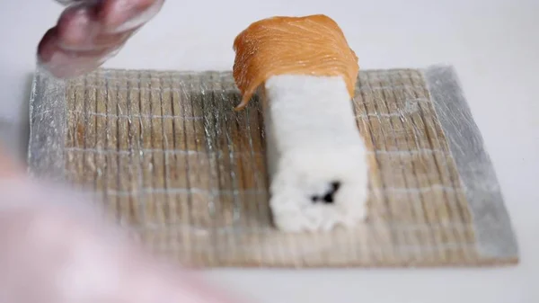 Närbild av kock händer förbereda japansk mat att göra sushi på restaurang. Ung kock som serverar traditionella moderna japan måltid i industriella kök. Närbild skytte vapen av cook-kocken att göra rullar — Stockfoto