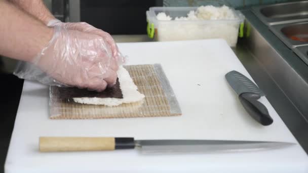 Руки делают суши-ролл. Суши шеф-повар демонстрирует мастерство. Знаменитая японская кухня — стоковое видео