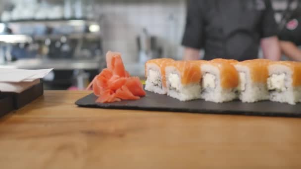 Close-up - o garçom colocou o sushi a bordo na mesa no restaurante — Vídeo de Stock