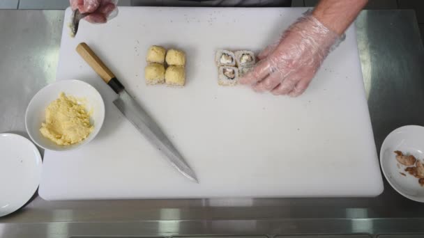 Chef en el restaurante preparando y cortando rollos de sushi comida saludable. vista superior — Vídeo de stock