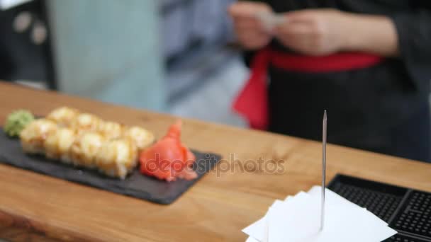 Close-up - o garçom colocou o sushi a bordo na mesa no restaurante — Vídeo de Stock
