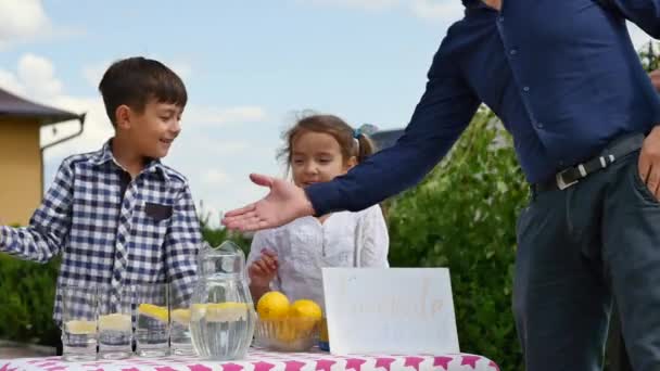 Dwa małe dzieci są sprzedaży lemoniady na stoisku domowej lemoniady na słoneczny dzień ze znakiem cena pojęciem przedsiębiorcy — Wideo stockowe