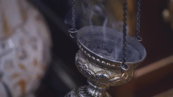 Курящее устройство посреди ритуала. Крупный план замедленной съемки дымящегося устройства посреди ритуала в центре церкви — стоковое фото