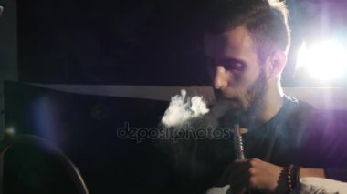 Genç adam sigara nargile ve yakın çekim sağlar karanlık bir odada duman halkaları