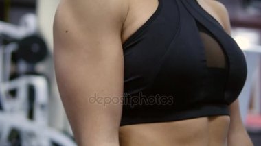 Çekici sporcumuz salonunda dumbbells ile eğitim. Çok kadın sporcunun kollarını iki yanda yükselterek kapatın. Crossfit egzersiz yaparken kameraya gülümseyen güçlü kız