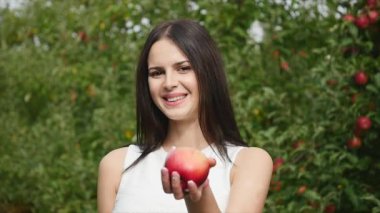 Genç kadın etrafında ve güneşin elma ağacı önünde kameraya poz beyaz bir elbise giymiş Bahçe çiçek. yakın çekim