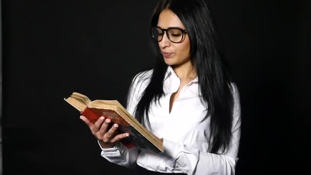 Portrait attrayant livre de lecture femme. belle jeune brune aux cheveux longs portant en chemise blanche posant en studio — Video