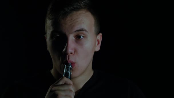 Lenyűgöző füst köröket tett egy fiatal férfi, aki használja az elektronikus cigaretta. A végén ő küld a legnagyobb füst kör jobb kezét a kamera — Stock videók