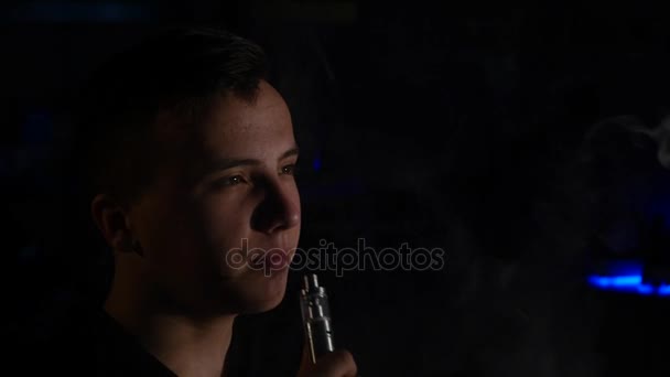 Hombre fumar vapor de cigarrillo electrónico sobre fondo negro — Vídeo de stock