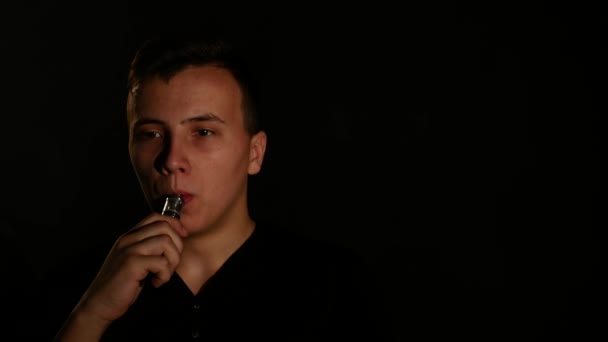 Mann raucht elektronische Zigarette Dampf auf schwarzem Hintergrund — Stockvideo