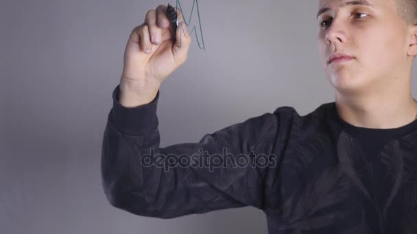 En ung man målar på glas whiteboard — Stockvideo