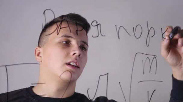 Close-up de um homem que escreve fórmulas em um quadro branco de vidro — Vídeo de Stock