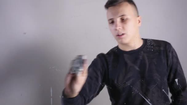 Jovem homem limpeza vidro quadro branco de perto — Vídeo de Stock
