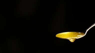 Siyah arka plan karşı kaşık akan bal