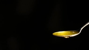 Siyah arka plan karşı kaşık akan bal