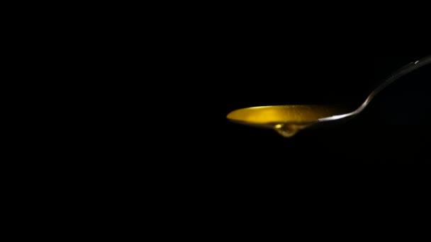 Honey Flowing from Spoon against Black Background — Stock Video