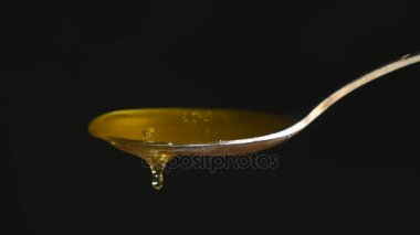 Siyah arka plan karşı kaşık akan bal