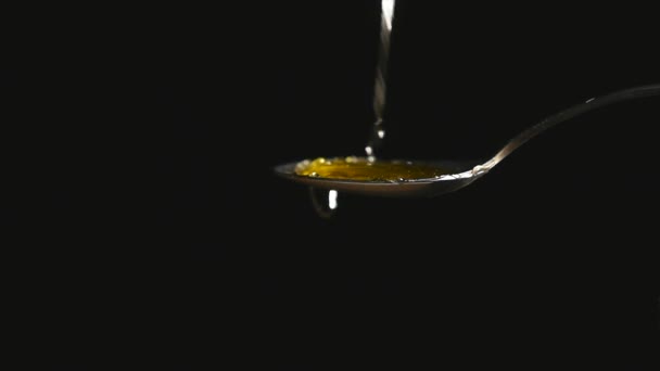 Honey dripping from the stainless tea spoon on black background — Stock Video