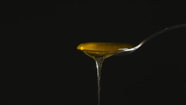 Honey Flowing from Spoon against Black Background — Stock Video