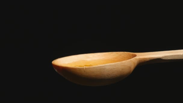 Honey dripping from a wooden honey dipper on black background — Stock Video