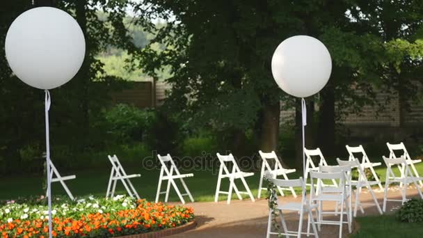 Bruiloft in de tuin, park opgericht. buiten huwelijksceremonie, viering. bruiloft gangpad decor. Rijen met witte houten lege stoelen op gazon voordat de ceremonie van het huwelijk — Stockvideo