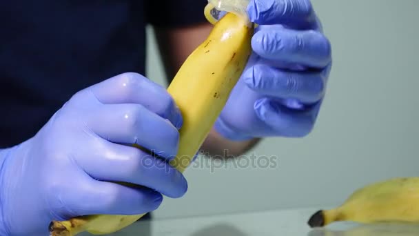 Una mano di uomo che mette un preservativo su una banana. Il concetto di sesso sicuro e prevenzione delle malattie sessualmente trasmissibili — Video Stock