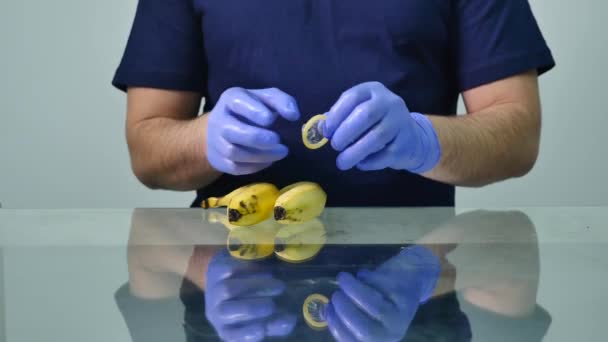 A mans hand att sätta på en kondom på en banan. Begreppet säker sex och förebyggande av sexuellt överförbara sjukdomar — Stockvideo