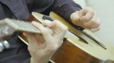 Yakın çekim, bir adamın elinde bir gitar çalmak