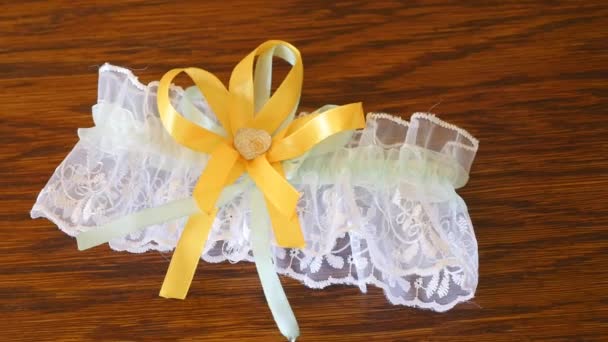 Красивые невесты желтая свадебная подвязка лежит на столе — стоковое видео