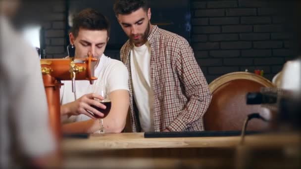 Two young men friends sitting in bar and talking with each other while drinking beer — Stock Video
