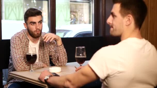 Zwei befreundete junge Männer sitzen in der Bar und unterhalten sich beim Biertrinken — Stockvideo