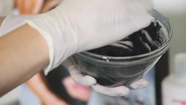 Kosmetikerin drückt Sahne aus einem Schlauch auf eine Glasuntertasse. Hände in Arzthandschuhen — Stockvideo