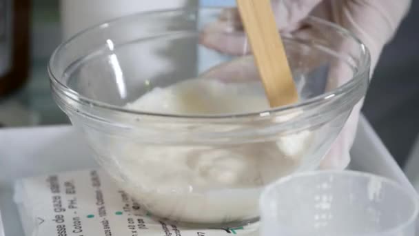 A beautician mixes facial mask with a brush. Young cosmetologist mixes cosmetic cream in small container. Mixing cosmetic cream — Stock Video