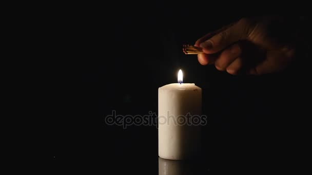 Руки зажгли свечу на черном фоне — стоковое видео