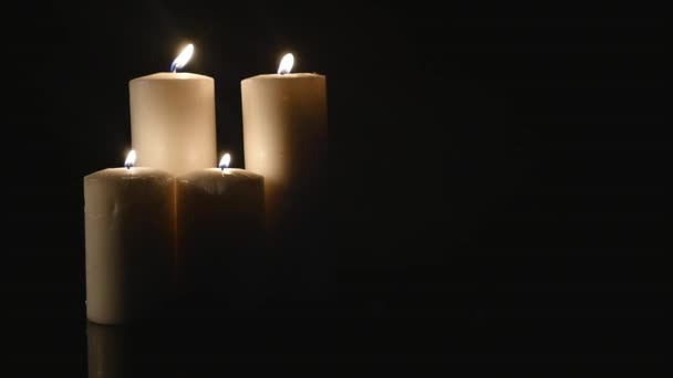 Cuatro velas blancas encendidas sobre fondo negro — Vídeos de Stock