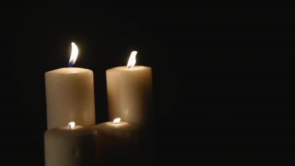 Cuatro velas blancas encendidas sobre fondo negro — Vídeos de Stock