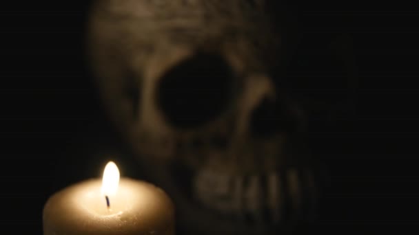 Vier brennende Kerzen und ein Totenkopf auf schwarzem Grund. Nahaufnahme — Stockvideo