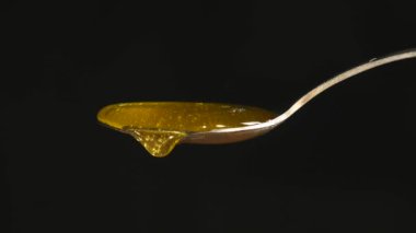 Siyah arka plan karşı kaşık akan bal