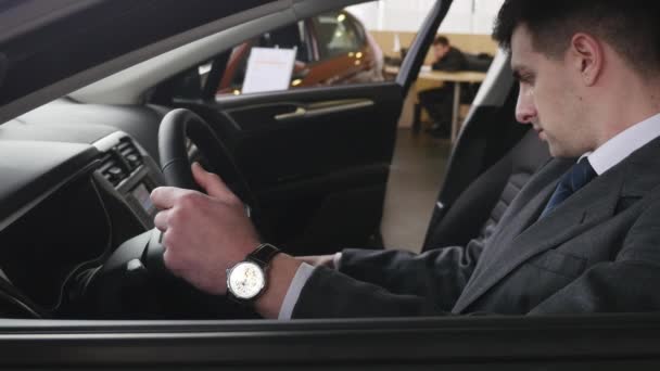 Een man inspecteert interieur van het voertuig. Auto business, auto verkoop, technologie en mensen concept - gelukkig man met autodealer in autoshow of salon. Jonge man met een verkoper in een motor show — Stockvideo