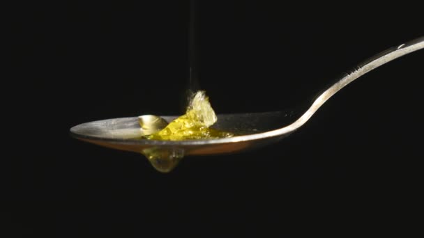 Miel goteando de la cuchara de té inoxidable sobre fondo negro — Vídeo de stock