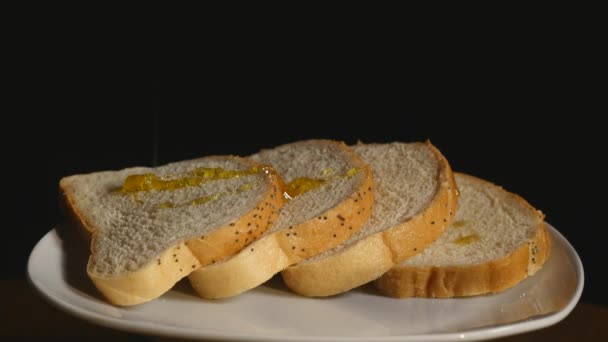 Toastbrot mit fließenden Honig auf schwarzem Hintergrund — Stockvideo