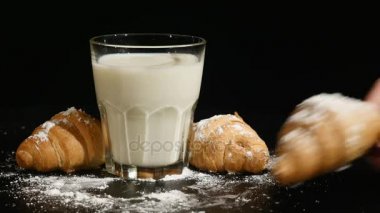 bardak süt kruvasan siyah bir arka plan ile. kruvasan el koyar