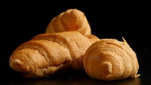 Tres croissants giran sobre un fondo negro — Vídeos de Stock