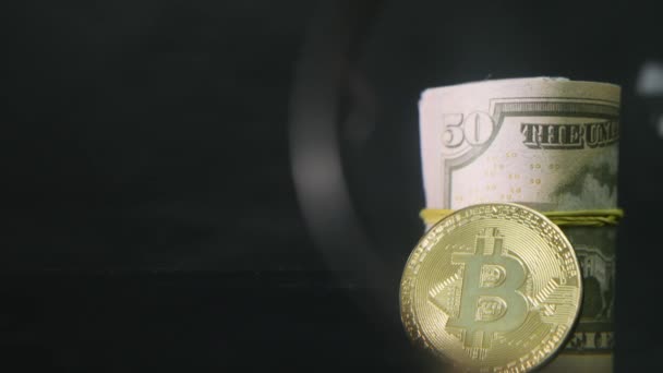 Bitcoin coin et les billets en dollars torsadés sur un fond noir — Video