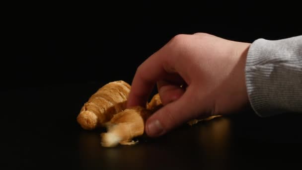 Hand nimmt Croissant auf schwarzem Hintergrund — Stockvideo