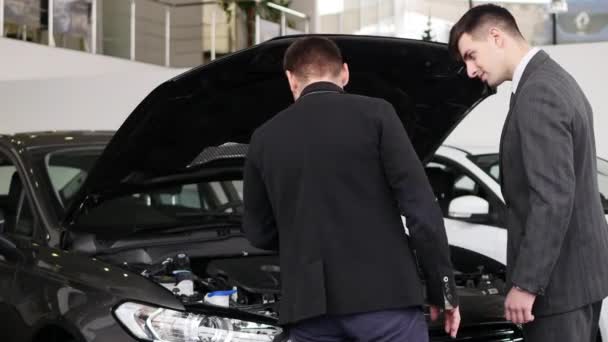 Jovem olhando para o compartimento do motor na concessionária — Vídeo de Stock