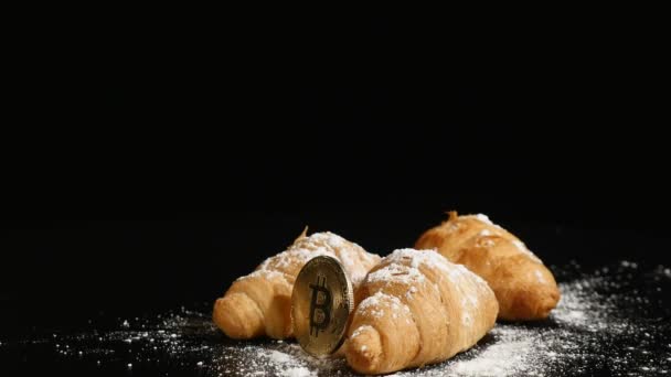 Tre croissanter med bitcoin mynt rotera på svart bakgrund — Stockvideo