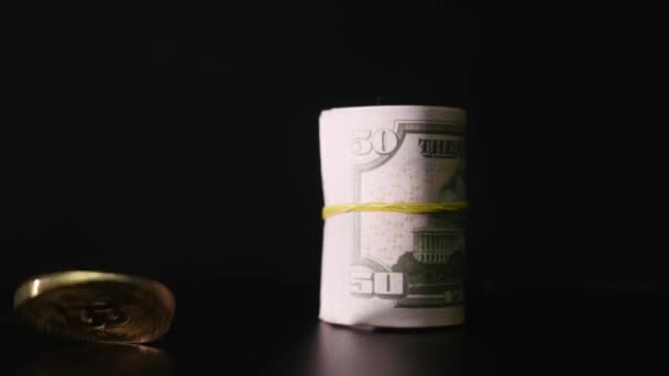 Bitcoin mynt och tvinnade dollar sedlar på svart bakgrund — Stockvideo